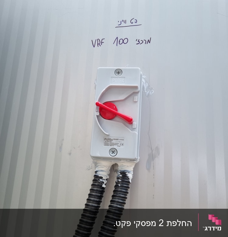 מתג חשמלי עם ידית אדומה ושני צינורות גמישים